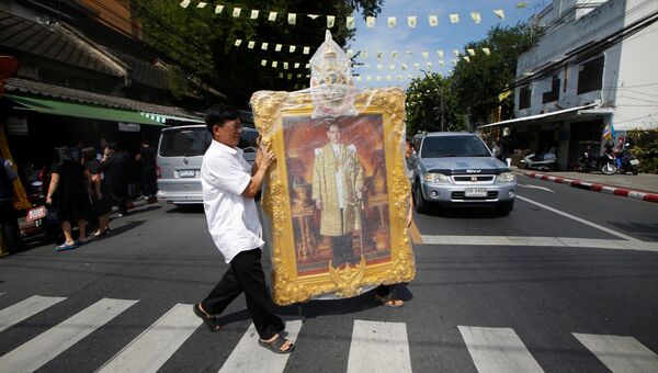 Люди с портретом короля Таиланда Пхумипона Адульядета на улице в Бангкоке