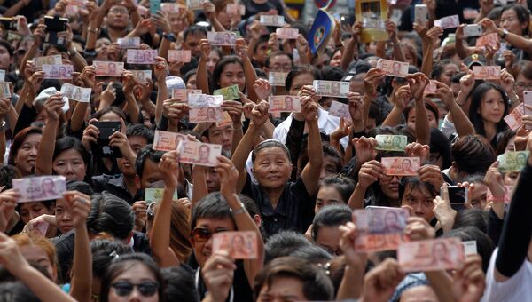 Люди с изображениями короля Таиланда Пхумипона Адульядета на денежных банкнотах в Бангкоке, Таиланд