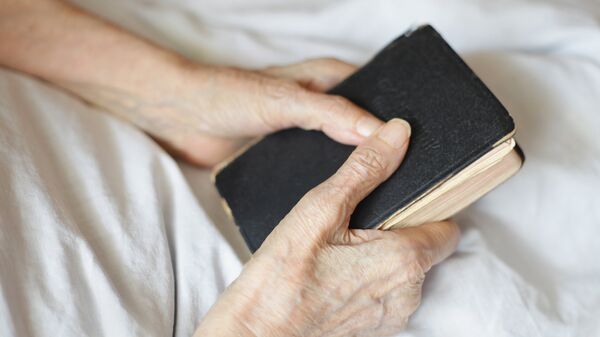 Библия в руках пожилого человека 