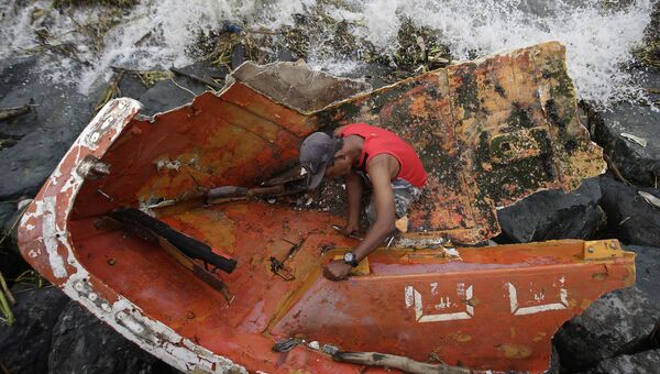 Мужчина восстанавливает лодку после тайфуна Лавин на Филиппинах