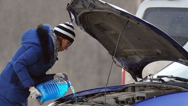 Женщина заливает незамерзающую жидкость для омывания стекол автомобиля на МКАДе в Москве