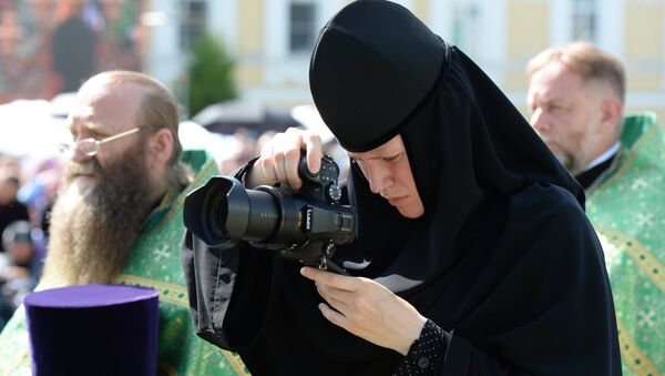 Монахиня с фотокамерой во время литургии