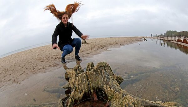 Девушка на берегу Балтийского моря, где вода отступила от берега на 20 метров, обнажив пни реликтовых деревьев