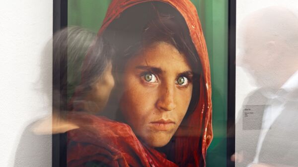 Портрет афганской девушки по имени Шарбат Гула на выставке работ фотографа Стива МакКарри