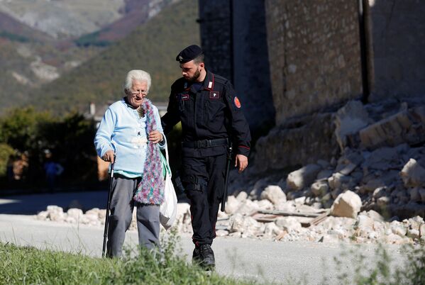 Карабинер c пожилой женщиной в пострадавшей от землетрясения коммуне Норча, Италия