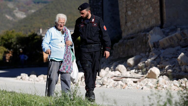 Карабинер c пожилой женщиной в пострадавшей от землетрясения коммуне Норча, Италия