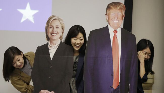 Студентки фотографируются с изображениями Дональда Трампа и Хиллари Клинтон в посольстве США в Токио. Архивное фото