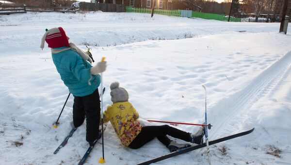 Дети катаются на лыжах в заснеженном селе Березовка в Томской области