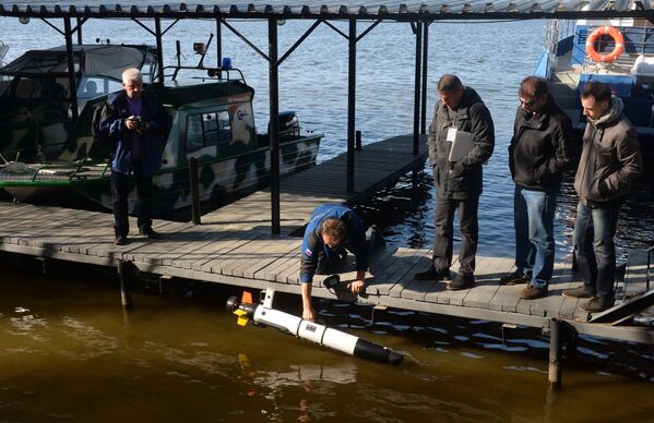 Мужчина погружает автономный необитаемый аппарат Iver2, предназначенный для экологического мониторинга качества воды
