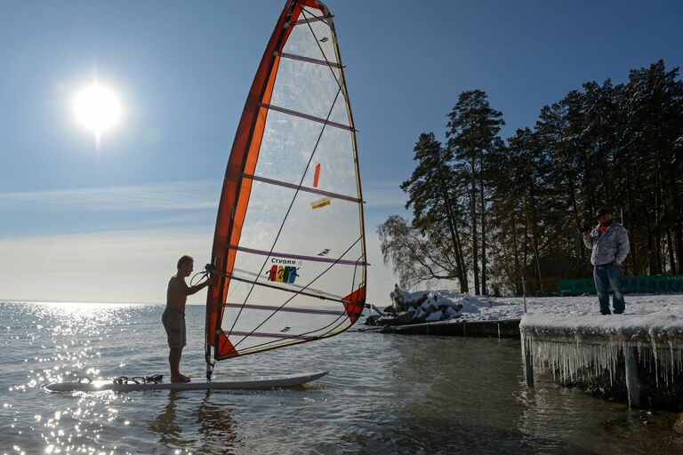 Спортсмен Александр Орлов (слева) занимается виндсерфингом при температуре воздуха около -5 градусов на водохранилище Новосибирской ГЭС у сёрф-станции Бумеранг