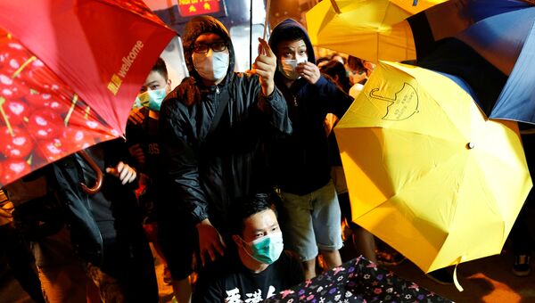Демонстранты используют зонты для защиты от перечного газа во время столкновений с полицией перед представительством КНР в Гонконге. 6 ноября 2016