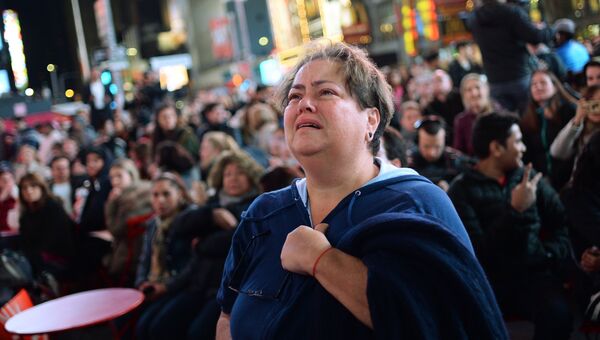 Женщина плачет на площади Таймс-сквер в Нью-Йорке у экранов с предварительными итогами подсчета голосов на выборах президента США.