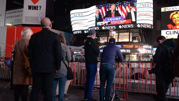 Горожане на площади Таймс-сквер в Нью-Йорке смотрят трансляцию выступления избранного президента США Дональда Трампа