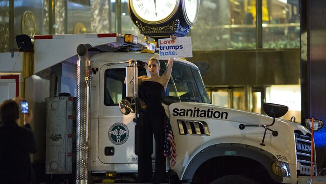 Певица Леди Гага с плакатом против кандидата в президенты США Дональда Трампа у башни Трампа в Нью-Йорке