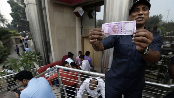Мужчина показывает новую купюру номиналом в 2000 рупий в Нью-Дели после денежной реформы в Индии