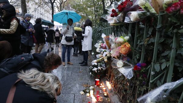 Люди приносят цветы и зажигают свечи у входа в клуб Bataclan в Париже