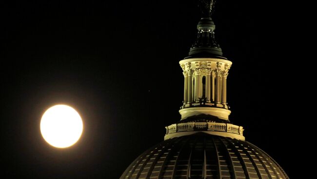 Луна поднимается над Капитолием накануне суперлуния в Вашингтоне, США. 13 ноября 2016