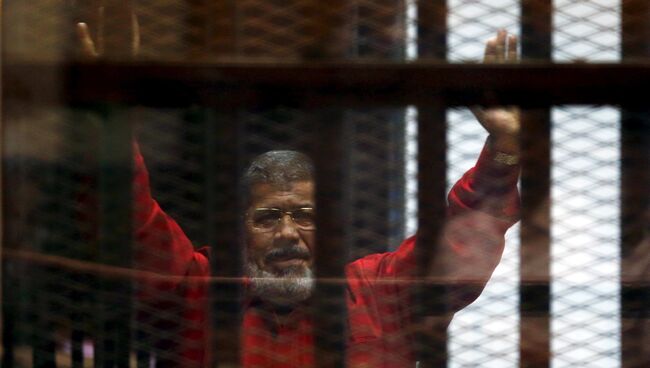 Свергнутый президент Египта Мохаммед Мурси приветствует своих юристов и людей из-за решетки