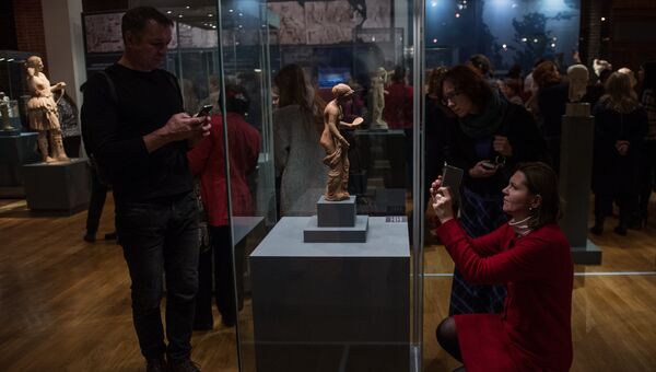 Посетители фотографирую терракотовую статуэтку Афродиты с зеркалом на открытии выставки Боги и герои Древней Греции