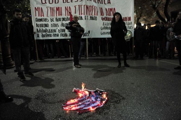 Демонстранты сжигают флаг во время акция протеста против визита президента США Барака Обамы в Афинах, Греция. 15 ноября 2016