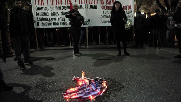 Демонстранты сжигают флаг во время акция протеста против визита президента США Барака Обамы в Афинах, Греция. 15 ноября 2016