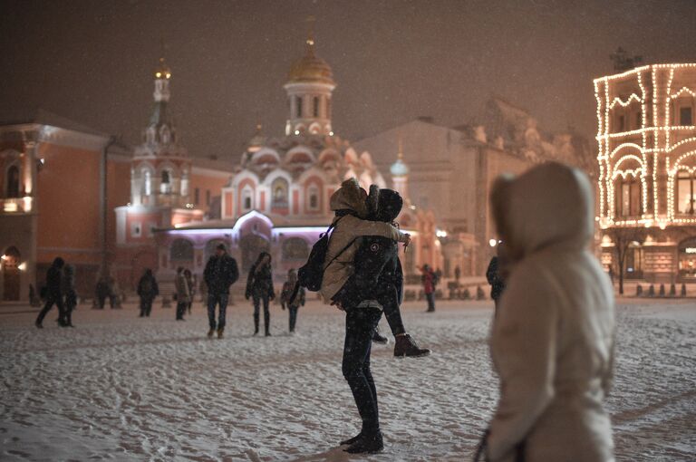 Прохожие на Красной площади в Москве во время снегопада