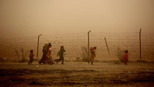 Сирийские дети гуляют во время песчаной бури в лагере для беженцев. Архивное фото