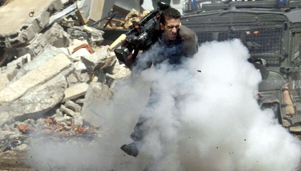 Телеоператор Исмаил Кадер укрывается от гранат в городе Рамалла, 5 апреля 2002