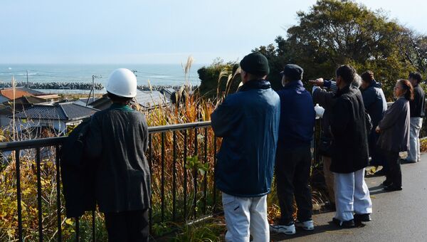 Жители смотрят на море после предупреждения о возможном цунами в Иваки, Япония
