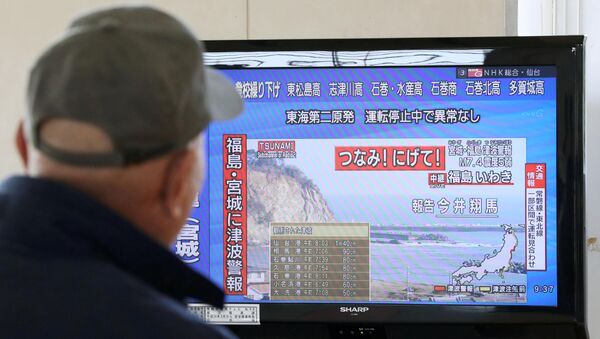 Мужчина смотрит телевизионный репортаж с предупреждением о цунами после эвакуации в Сендай, Япония