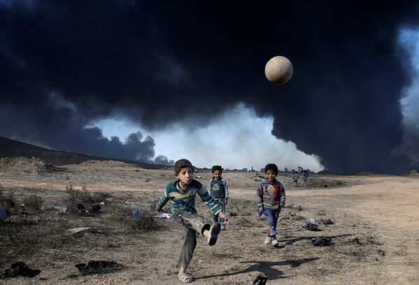 Дети играют в футбол в городе Кайяра, к югу от Мосула, Ирак