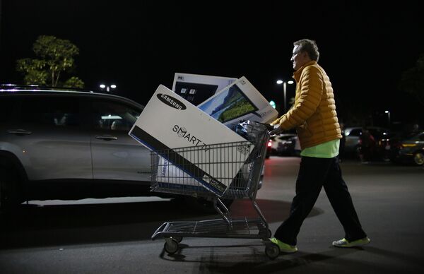 Покупатель выходит из магазина во время распродажи в Черную пятницу в Сан-Диего, штат Калифорния, США