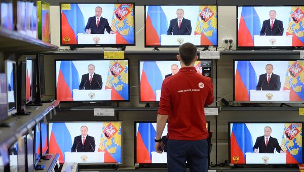 Мужчина смотрит трансляцию выступления президента России Владимира Путина с ежегодным посланием к Федеральному Собранию РФ в магазине по продаже цифровой и бытовой техники