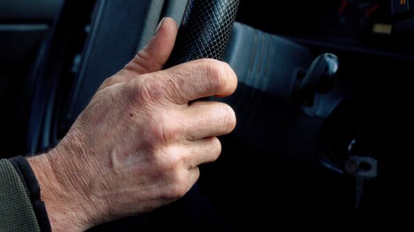 Рука пожилого мужчины на руле автомобиля