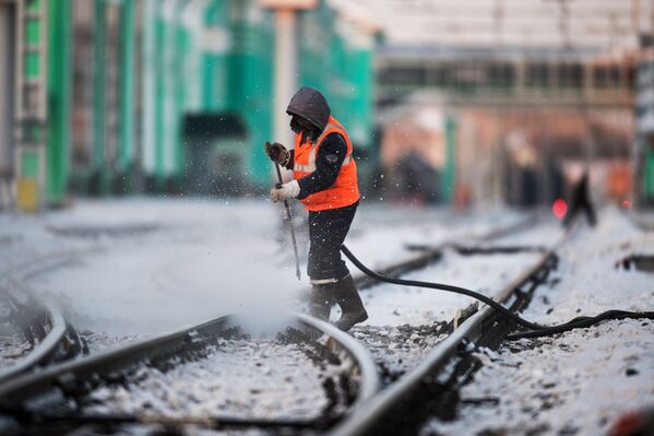 Рабочий очищает железнодорожный путь на станции Омск-Пассажирский в Омске