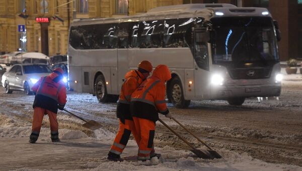 Сотрудники коммунальных служб убирают на улице снег во время снегопада в Москве