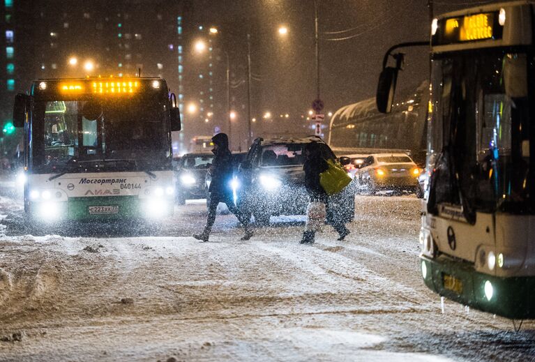 Прохожие переходят дорогу в Москве во время снегопада