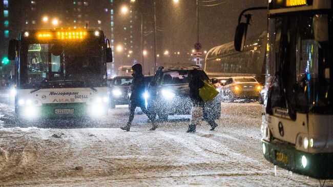 Прохожие переходят дорогу в Москве во время снегопада. Архивное фото