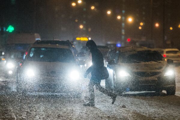 Прохожий переходит дорогу в Москве во время снегопада