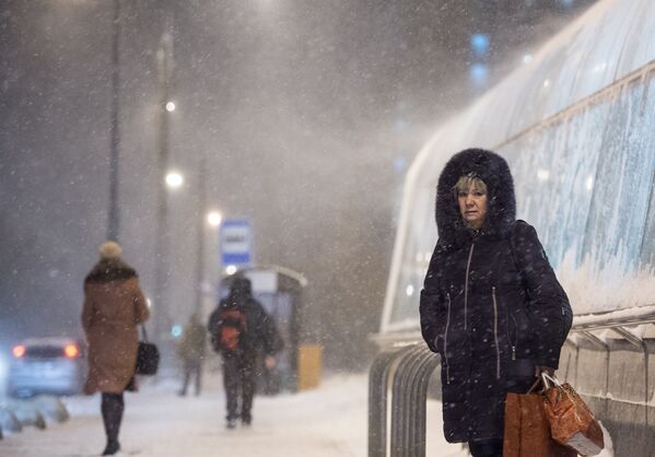 Прохожие у станции метро Новокосино в Москве во время снегопада