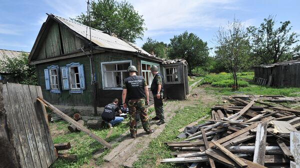 Сотрудники правоохранительных органов работают на месте попадания одного из фугасных снарядов в городе Донецке Ростовской области со стороны украинской территории. Июль 2014 года