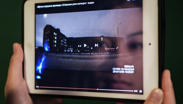 Девушка смотрит видеозапись падения небесного тела, заснятое жителями Хакасии. Архивное фото