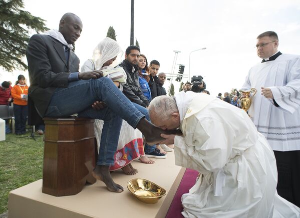 Папа римский Франциск во время омовения ног мигрантам в центре для беженцев в городе Кастельнуово-ди-Порто
