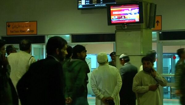 Люди смотрят репортаж об авиакатастрофе самолета авиакомпании PIA в аэропорту Беназир Бхутто в Исламабаде, Пакистан