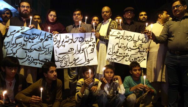 Люди держат свечи в память о жертвах авиакатастрофы самолета авиакомпании PIA в Мултане, Пакистан