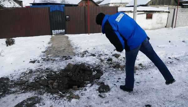 Сотрудник ОБСЕ осматривает воронку после обстрела украинскими силовиками. Архивное фото