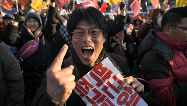 Протестующий радуется принятию решения об импичменте президенту Южной Кореи Пак Кын Хе у здания Национального собрания в Сеуле
