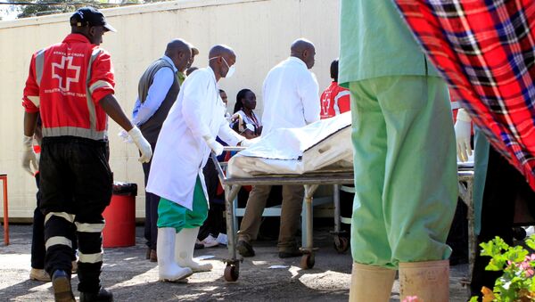 Сотрудники Красного Креста и морга везут тело погибшего в аварии с участием нефтяного трейлера в Кении