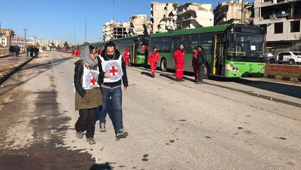 Сотрудники Красного креста ожидают выхода последней группы боевиков из восточного Алеппо