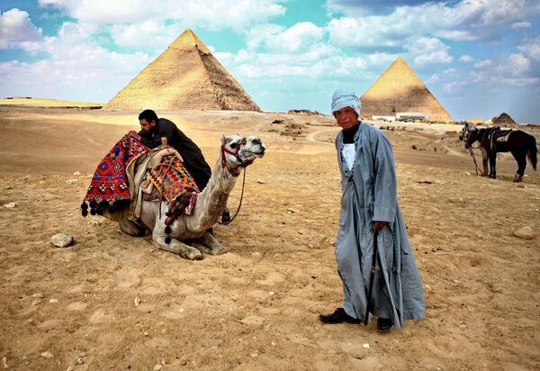 Местные жители стоят у пирамид в Гизе